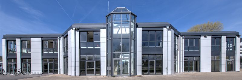 Zweigeschossiges Bürogebäude mit verglastem Treppenhausturm und hellen Fassadenpaneelen