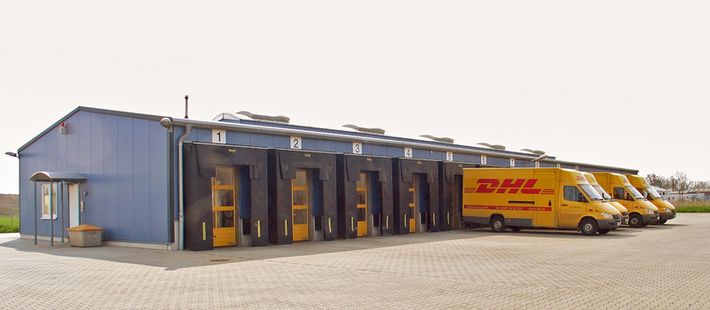Logistikhalle mit blauer Fassade, Verladetoren und gelben DHL-Transportern
