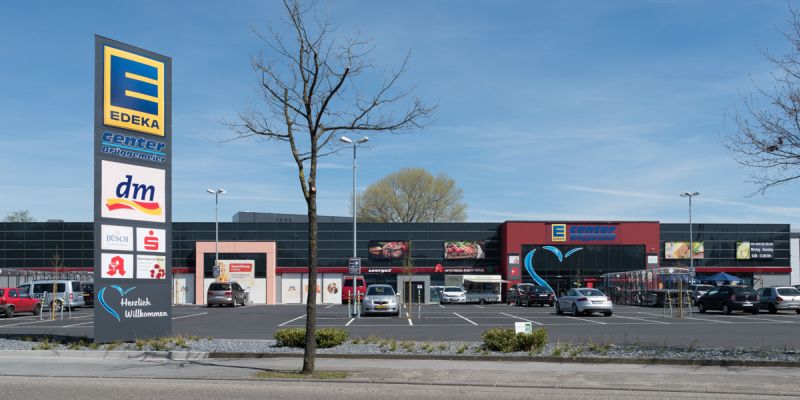 Fachmarktzentrum mit Werbepylon für EDEKA und dm, davor großer Parkplatz